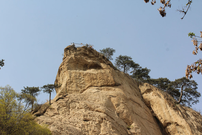 公路两旁全是松树,三四级的山风吹得一阵阵松涛声,悦耳动听,多少年没听见这声音了,太难得了。到达中院休息一阵子照了一圈。再往上走没见着导游图,只能跟着感觉走,一路上有好几个紧急避险撤离路线示意图,上面画的等高线,整不明白。上院后山陡峭的悬崖上围着铁栏杆,叫八仙顶。自己顺着小道向上去,问了一下路人,这是从双线天上八仙顶路,双线天用水泥修的阶梯,好走。过了双线天几步就到八仙顶了,上面有卧龙松、顽强松,在八仙顶照了一阵子,大风天气,朦朦胧胧的能遥望到骆驼峰,这里是个制高点,大小山峰全在脚下。又问了一下十八蹬在什么